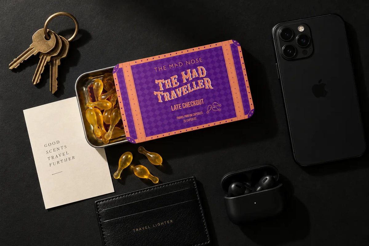 Pocket perfume capsules beside keys, phone, wallet and earphones in an everyday carry flat lay